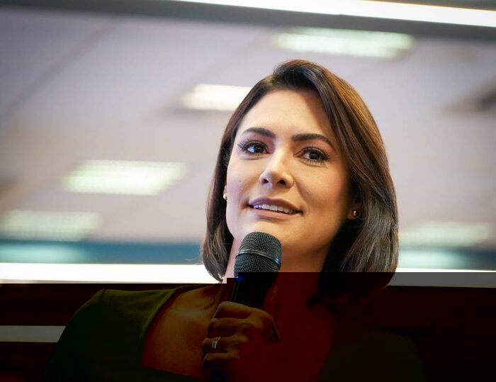 Michelle Bolsonaro discursando em evento público, microfone na mão