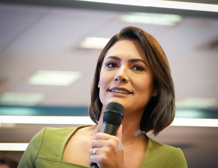 Michelle Bolsonaro, presidente do PL Mulher, sorrindo e segurando um microfone durante evento do partido